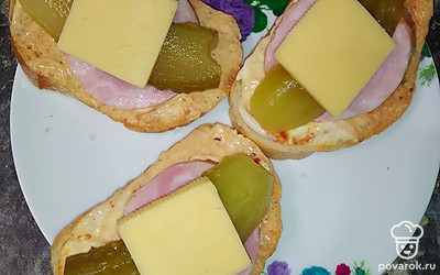 Поверх огурцов выложить нарезанный квадратиками сыр. Убрать бутерброды на минуту в микроволновку до расплавления сыра.