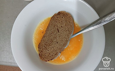 Обмакните ломтик хлеба в яичной смеси с одной стороны.