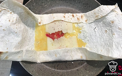 Затем выложите помидор и сыр. Начните закрывать лаваш, делая конверт.