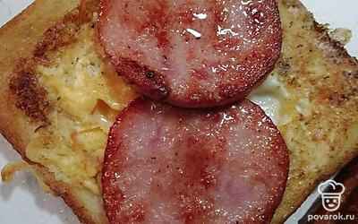 Перевернуть ломтики, немного обжарить с другой стороны и выложить на тарелку. Сверху положить 2 кусочка предварительно обжаренной колбасы.