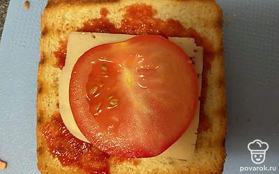 Помидор помойте, нарежьте тонкими пластиками и выложите поверх сыра.