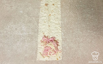 Лаваш нарежьте на полосочки. На полосочку из лаваша выложите начинку из сыра и колбасы.