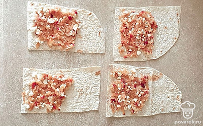 На лаваш выложите яблочную начинку и распределите. Скрутите лаваш в трубочки.