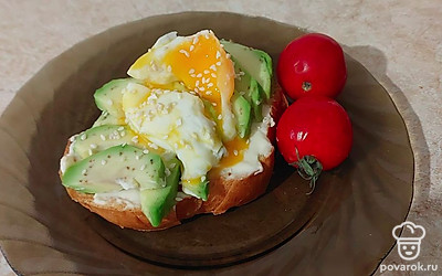 Тост из хлеба смазываем сыром, выкладываем сверху ломтики авокадо и яйцо.