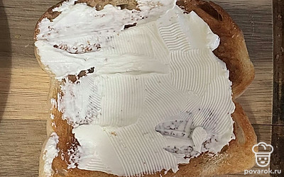 Смажьте ломтик хлеба творожным сыром.