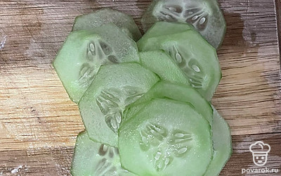 Очистите огурец и нашинкуйте кружочками. Выложите ломтики рыбы и огурца на тост.