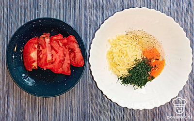 В миску добавляем яйцо, сыр, зелень, соль и перец по вкусу. Помидор нарезаем ломтиками.
