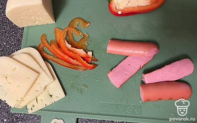 Подготовьте все ингредиенты заранее. Перец помойте, нарежьте тонкими пластинками. Отрежьте сыр, сосиску разрежьте вдоль и пополам.