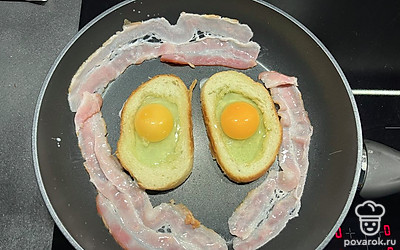 Как только хлеб поджарится с одной стороны, переворачиваем и разбиваем яйца в хлеб.