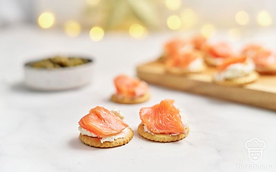 Положите сверху, слегка свернув, по 1 кусочку лосося. Разложите получившиеся канапе на подносе. Добавьте на каждое по 2-3 каперса и по 2-3 маленьких кисточки укропа. 