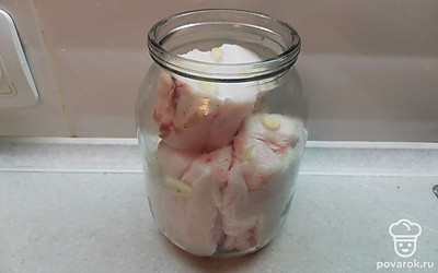 Сало сложить в банку, переложив нарезанным чесноком.
