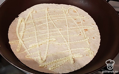 На разогретую и смазанную маслом сковороду выкладываем 1 тортилью и делаем сеточку из майонеза.