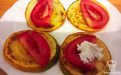 Помидор нарежьте тонкими дольками, выложите их на жареные ломтики кабачка, а сверху намажьте творог.