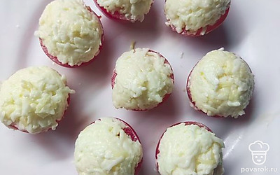 Смешать чеснок, майонез и сыр. Аккуратно чайной ложкой выложить смесь на каждую помидорку, формируя шапочку.