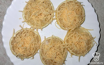Посыпаем кружочки лимонов тертым сыром.
