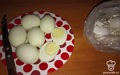 Вареные яйца остужаем под холодной водой, чистим и разрезаем пополам.