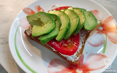 Почистить и нарезать авокадо, немного сбрызнуть лимонным соком. Выложить авокадо на помидор. 