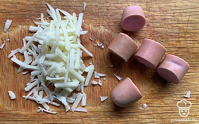 Сыр натереть на терке, сосиску нарезать.