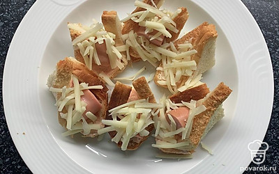 Выложить кусочки сосисок и сверху выложить сыр. Отправить на пару минут в микроволновку или духовку, чтобы сыр расплавился.