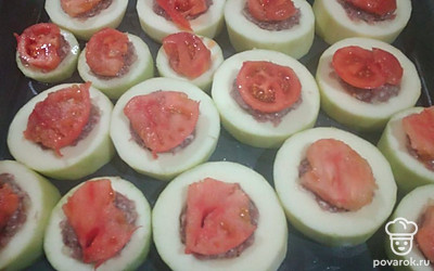 Фарш посолить, поперчить, выложить в середину кабачка. Сверху положить дольку томата.