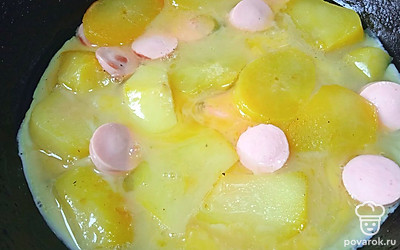 Переверните картофель и сосиски. Залейте взбитыми с солью яйцами. Накройте крышкой.