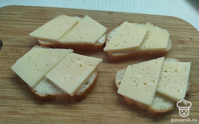 На каждый кусочек хлеба положите тонкие ломтики сыра. 