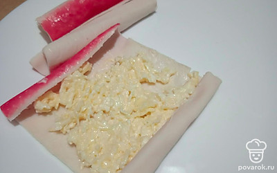 На каждую крабовую палочку положите сырную начинку.