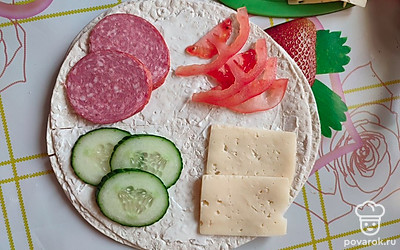 Далее выложить по секторам колбасу, сыр, огурцы и помидор. 