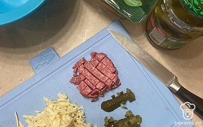 Нарежьте кубиками колбасу (ветчину) и огурцы, натрите сыр.