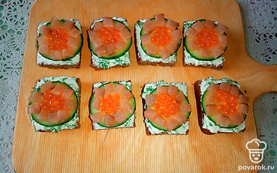 Нарежьте слабосоленую красную рыбу полосками, а затем небольшими квадратиками. Выложите получившиеся квадратики из рыбы вокруг красной икры.