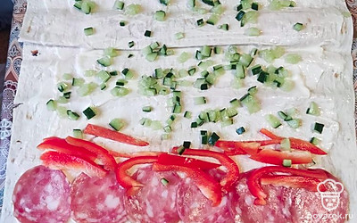 Смажьте лаваш соусом, вниз выложите колбасу, а рядом положите полоски перца. Огурец распределите по всему лавашу.