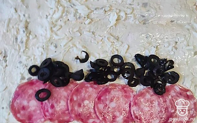 Выложите на лаваш яичную смесь, распределив по всей поверхности. На нижний край выложите колбасу и колечки маслин. Сверните в тугой рулет.