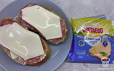 На колбасу выложить ломтики сливочного сыра. Запекать бутерброды в микроволновке 30 секунд.