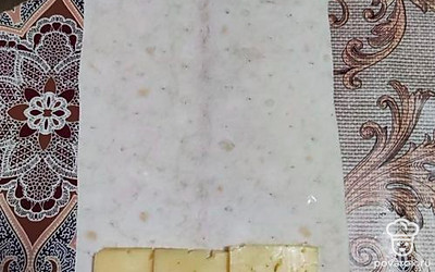 На полоску лаваша выкладываем сосиску и ломтики сыра. 