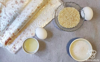 Подготовьте продукты. Нарежьте лаваш полосками по 8-10 сантиметров в ширину. Разогрейте сковородку. 1 яйцо взбейте, 1 яйцо сварите. Рис хорошо промойте и отварите до готовности.