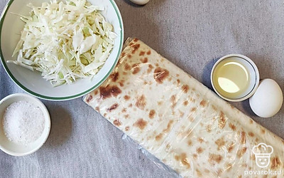 Подготавливаем продукты. Нарезаем лаваш полосками по 8-10 сантиметров в ширину. Разогреваем сковородку, взбиваем 1 яйцо. Шинкуем капусту, отвариваем 1 яйцо.