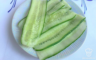 Помойте огурцы, отрежьте кончики. С помощью овощечистки нарежьте огурец слайсами.