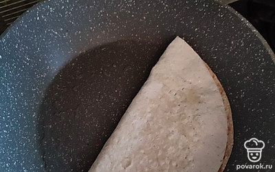 Складываем лаваш пополам, накрывая начинку второй половинкой круга. Получается полукруг, как на фото. Накрываем крышкой, убавляем огонь на плите до минимума. Ждем минуты 3.