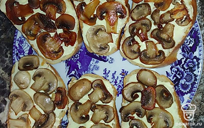 Выложить обжаренные грибы на хлеб. Сыр нарезать на ломтики, также выложить поверх шампиньонов. Убрать на минуту в микроволновку до расплавления сыра.