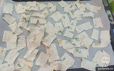 Выкладываем ломтики лаваша на противень, застеленный пергаментной бумагой, и ставим в разогретую до 180 градусов духовку на 15 минут. 