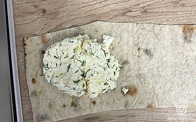 Нарежьте лаваш на длинные полосы. Выложите по одной столовой ложке получившейся смеси на лаваш. Сверните треугольником.