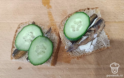 Выложите огуречные кольца на бутерброд со шпротами.