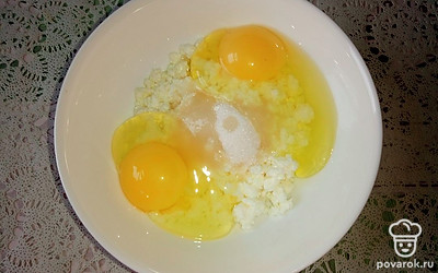 Вбейте 2 яйца к творогу с сахаром и хорошо перемешайте, чтобы сахар полностью растворился.