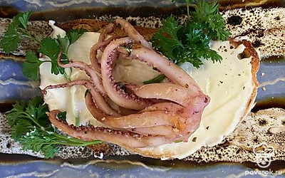 На брускетту выложите осьминожку и добавьте зелень.