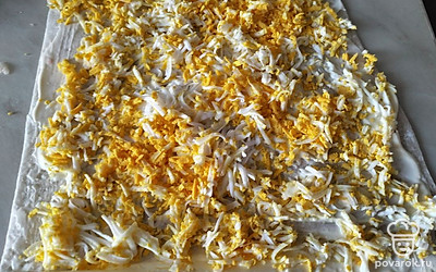 Отвариваем яйца, остужаем, чистим и натираем на терке. Равномерно распределяем по лавашу.