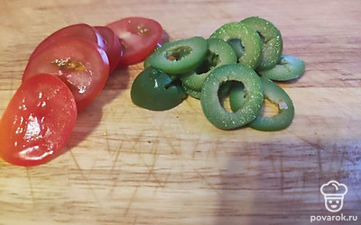 Нарежьте томаты и оливки колечками. Выложите на сыр слоями сначала помидоры, затем оливки. 