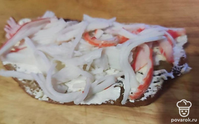 На сыр выложите палочки, разобранные на волокна. Сверху положите помидорки и посыпьте луком. 