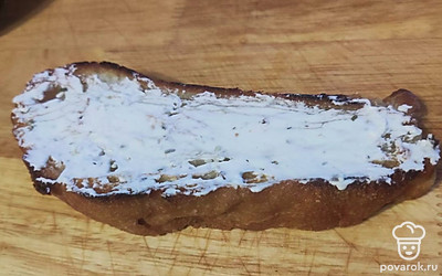 Натрите хлеб с обеих сторон чесноком и сверху намажьте сыром. Уложите огурчики и выложите шпроты.