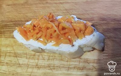 Мелко нарежьте морковь и выложите первым слоем на брускетту, сверху положите шпроты. 