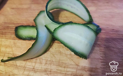 Огурец нарежьте овощечисткой на слайсы.